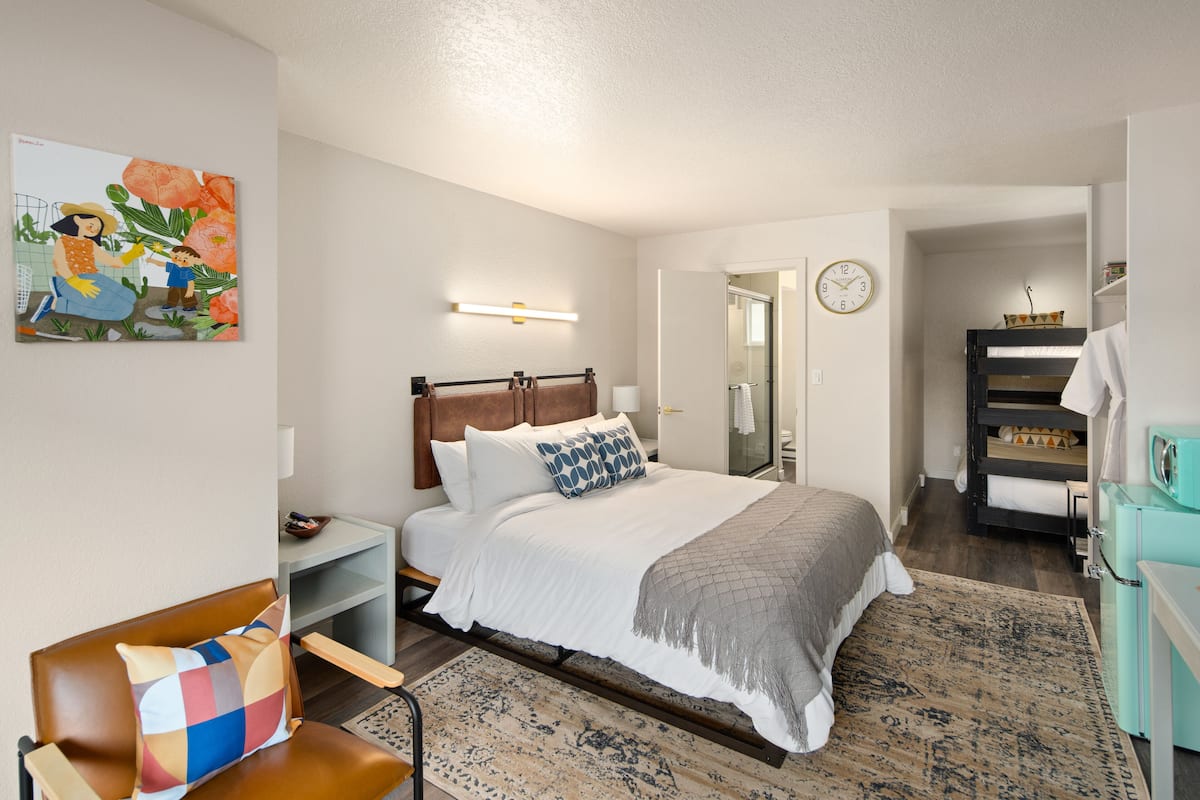 A bedroom with a bed, bedside tables, a chair, a painting, a clock, and a wardrobe.
