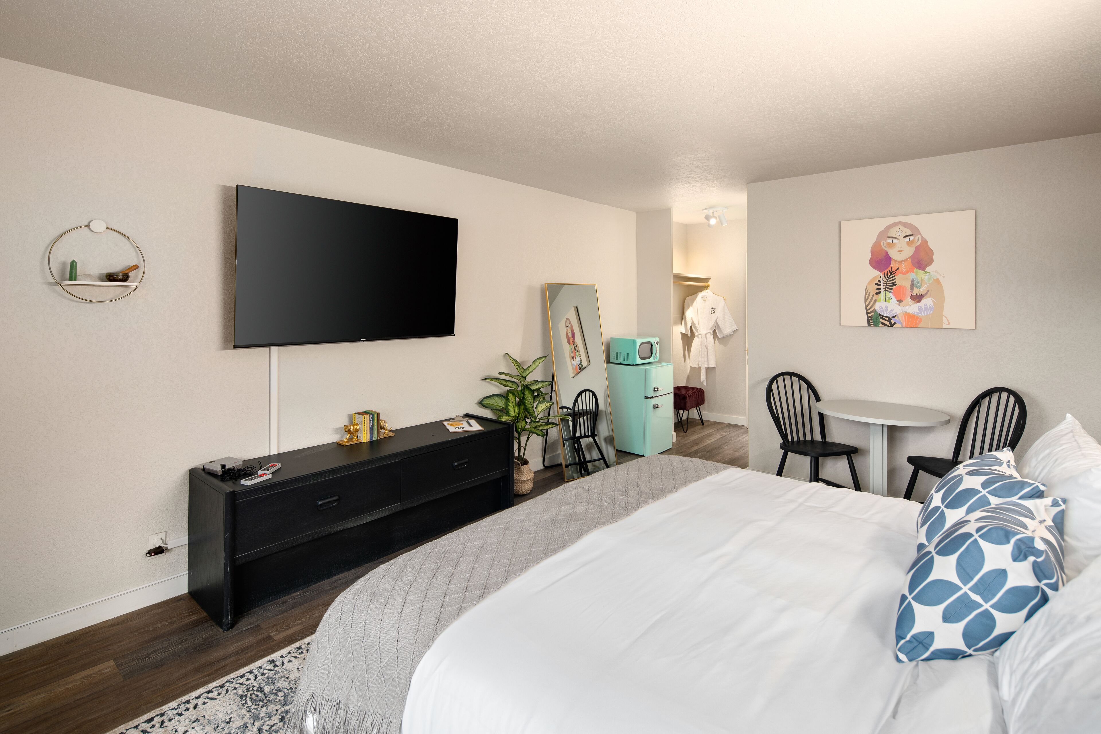 Une chambre d’hôtel moderne dotée d’un grand lit, d’un téléviseur à écran plat, d’un bureau avec une chaise et d’une petite table.
