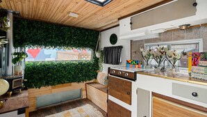 A compact kitchen with a wooden ceiling, a green wall, and a window with a view of a colorful building. - Hotel McCoy Pullman - Art, Coffee, Beer, Wine (Pullman)