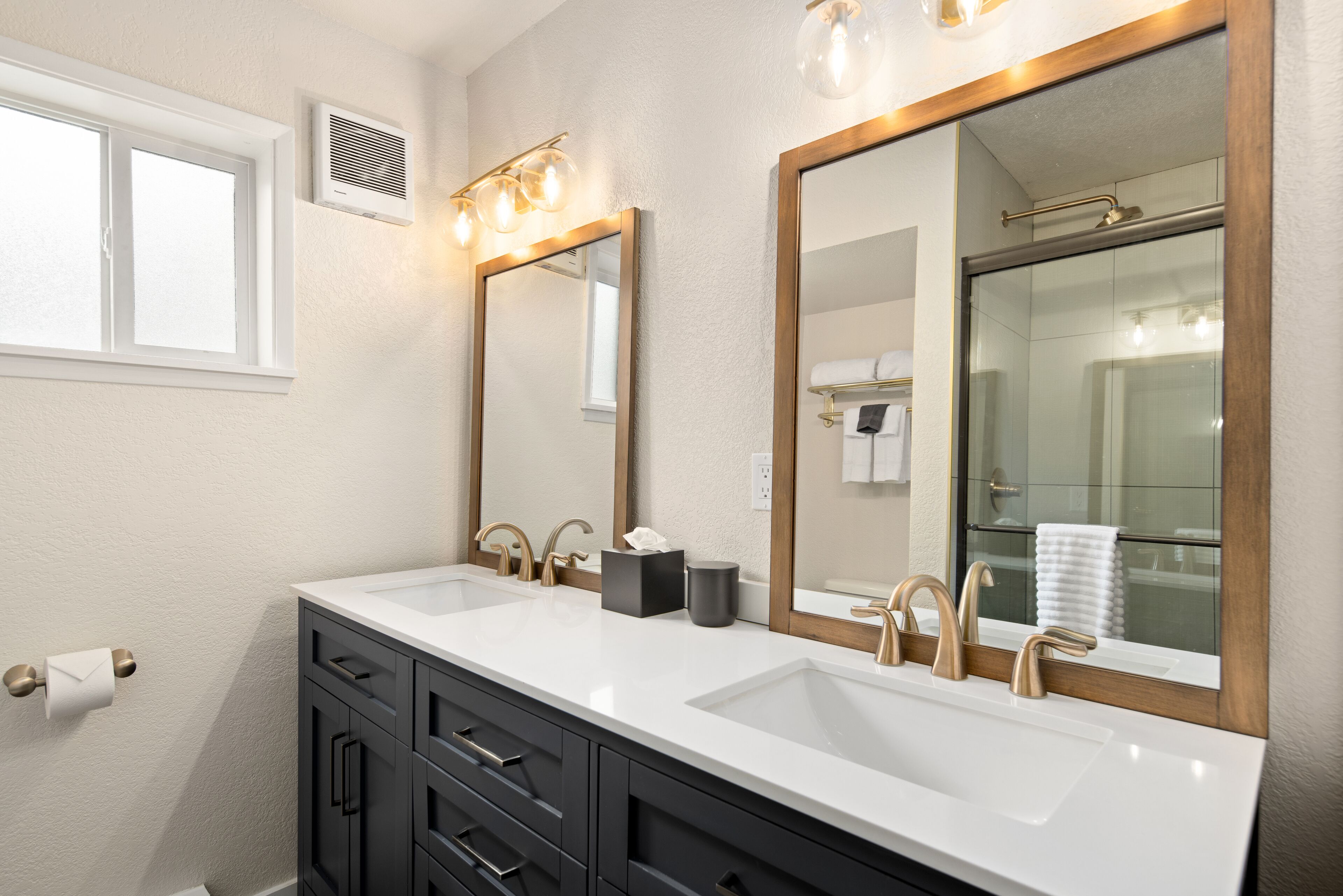 A bathroom with two sinks, a large mirror, and a window.