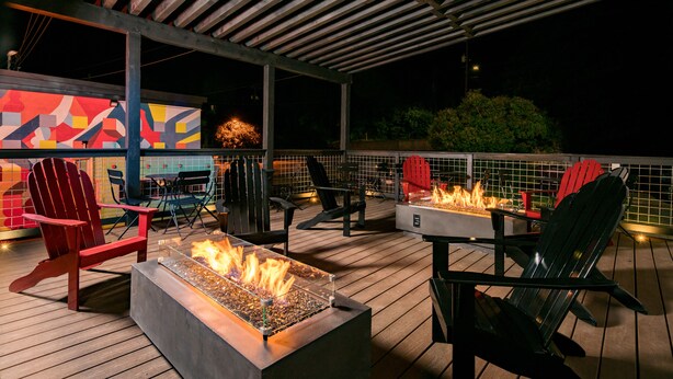 A deck with a fire feature, outdoor seating, and a colorful mural. - Hotel McCoy Pullman - Art, Coffee, Beer, Wine (Pullman)