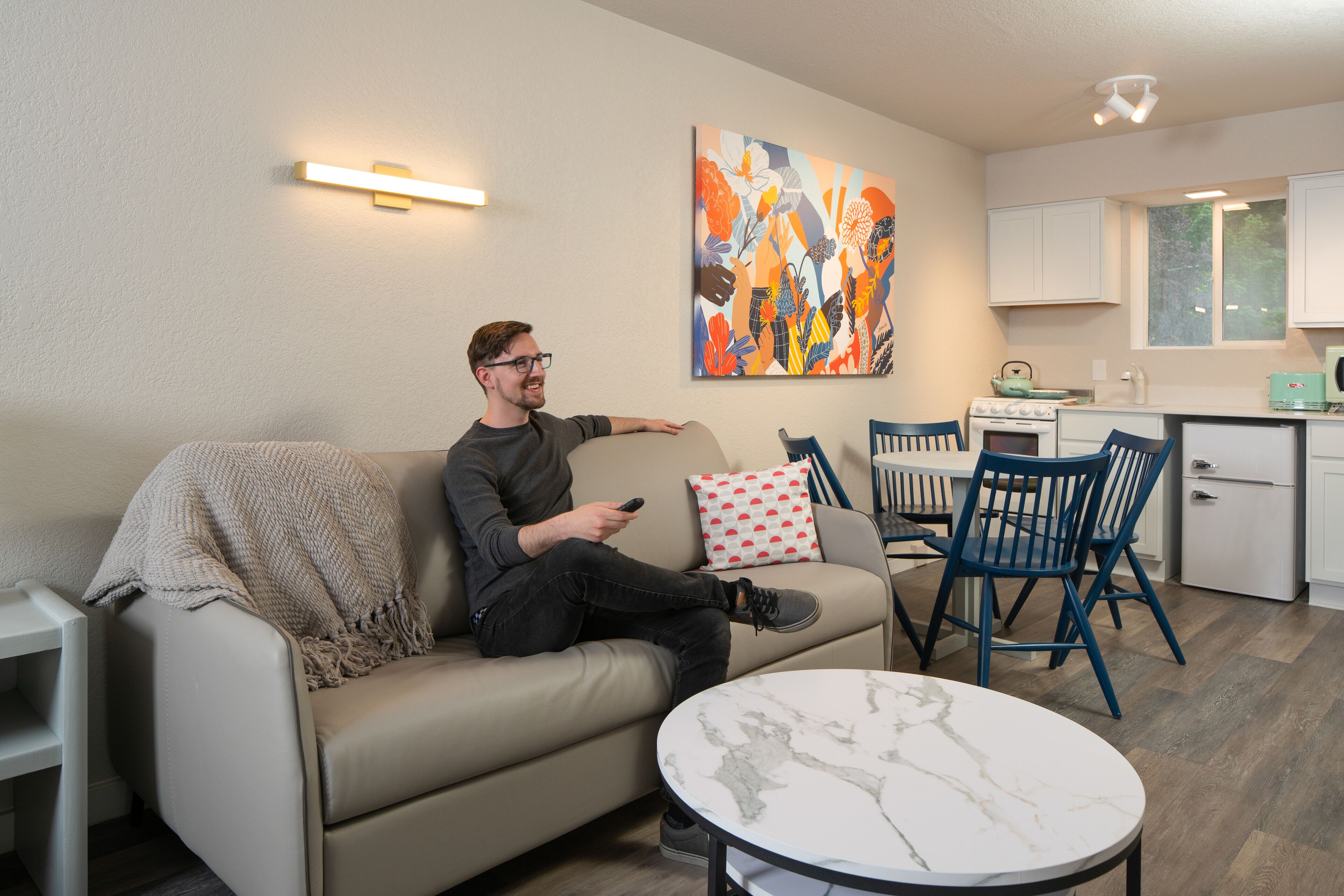 Una sala de estar moderna con un sofá, una mesa de centro y una cocina al fondo.