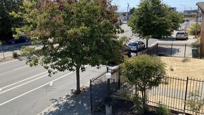 A street view with a motel sign, trees, and parked cars. - Bayview Motel (Emeryville)
