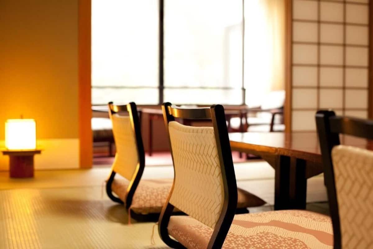 Una fila de sillas con asientos y respaldos acolchados, dispuestas en un comedor con una mesa al fondo.