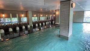 Une grande piscine intérieure dotée de plusieurs couloirs, d’installations sanitaires et d’un système d’éclairage au plafond.