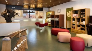 A reception area with a counter, information desk, and seating area with red chairs and ottomans. - Oka Hotel (Kanazawa)