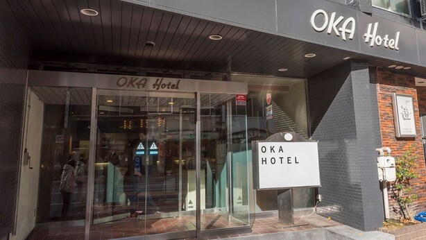 The exterior of the OKA Hotel with a modern facade, glass entrance, and signage. - Oka Hotel (Kanazawa)