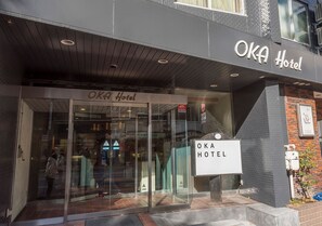 The exterior of the OKA Hotel with a modern facade, glass entrance, and signage. - Oka Hotel (Kanazawa)