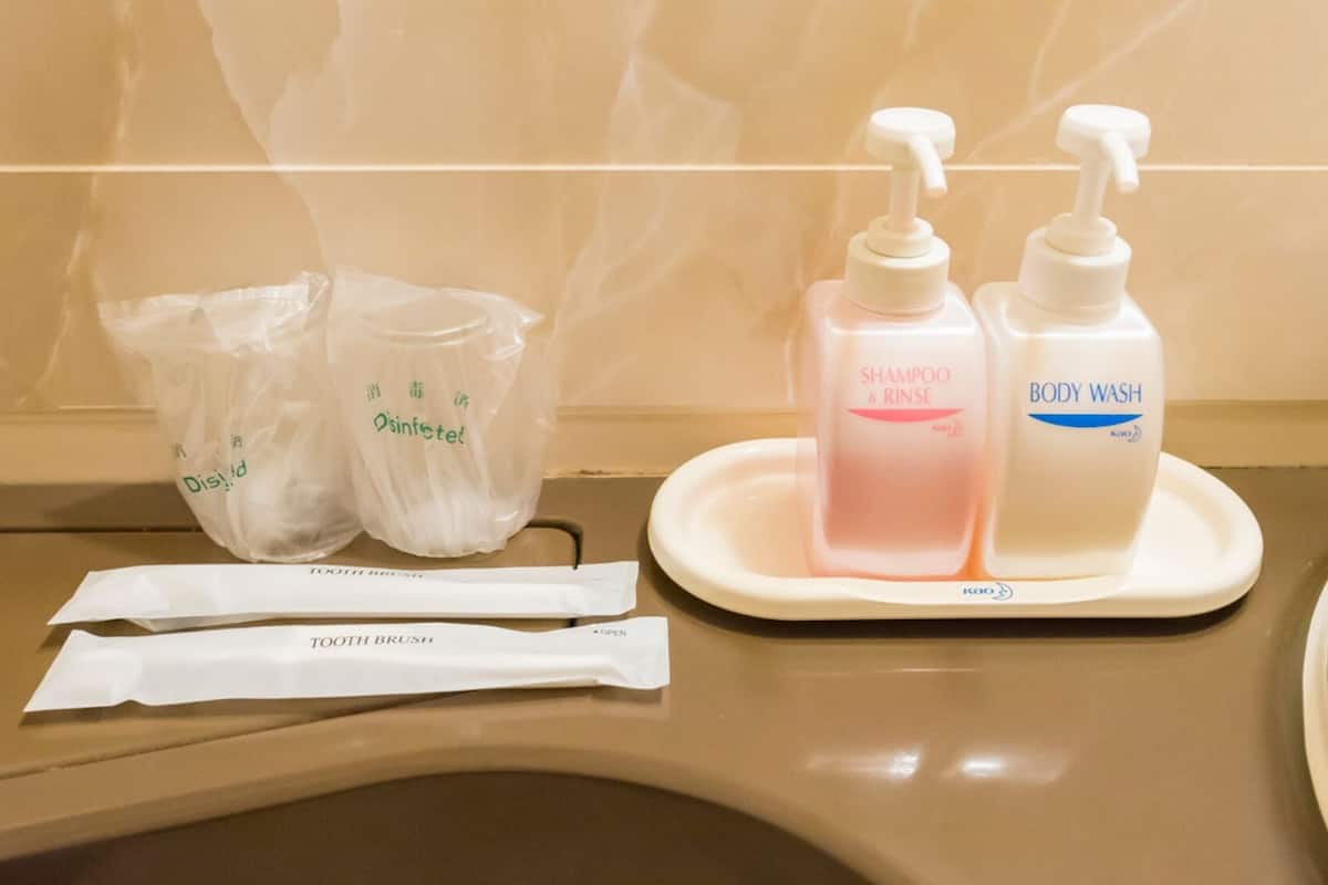Una encimera de baño con un cepillo de dientes, un estuche pequeño para viajes y dos botellas de champú y gel de baño.