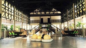 Um hall amplo com área de estar central, escada e vista para os andares superiores.
