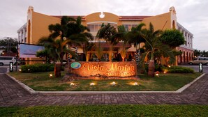 Exterior del hotel Vista Marina & Resort, con un letrero, palmeras y una entrada pavimentada.