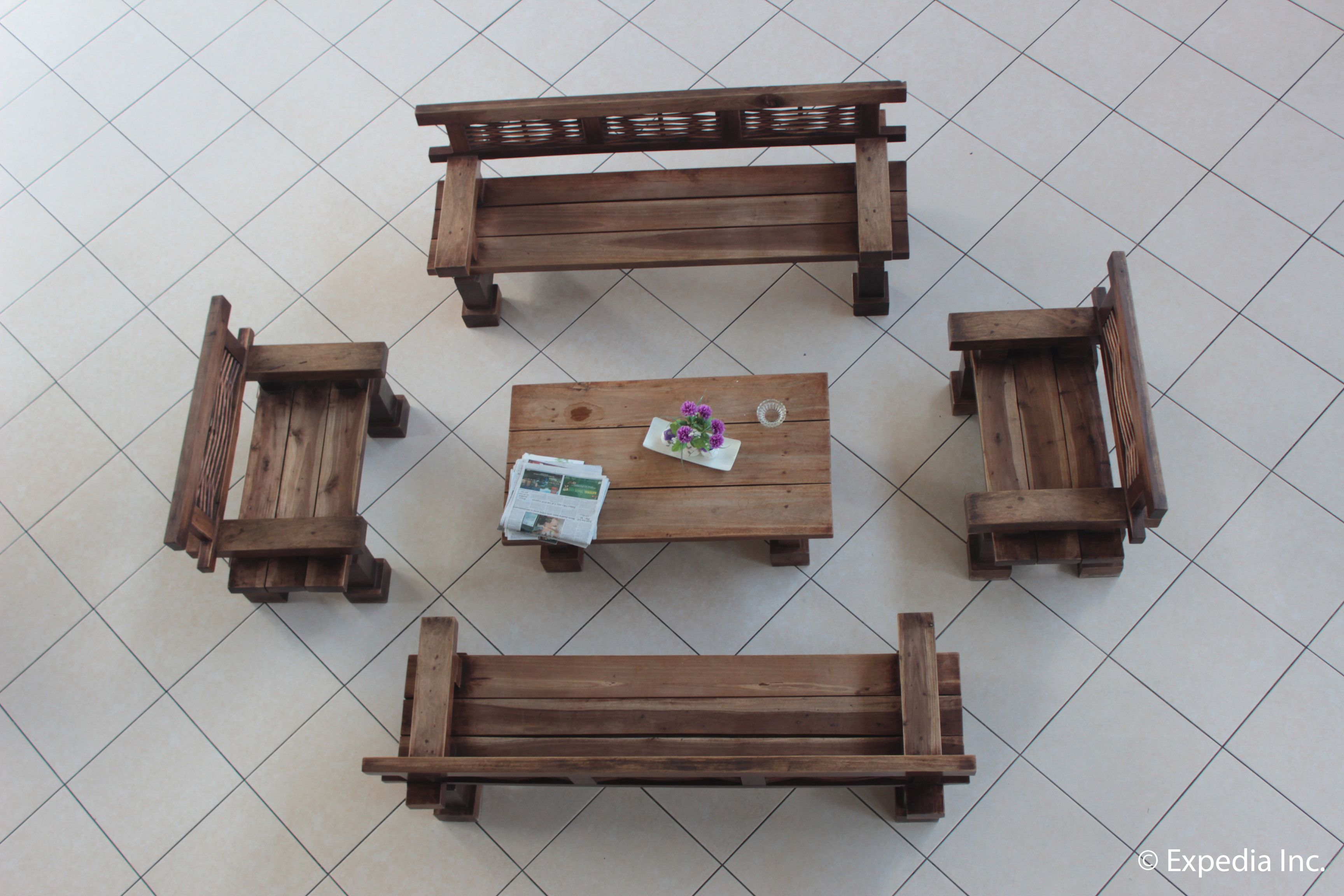Disposición cuadrada con muebles de madera, una mesa central y cuatro bancos.
