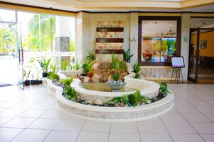 A reception area with a stone fountain, potted plants, and a seating area.