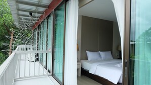 A hotel room with a balcony, a bed, and a sliding glass door leading to a balcony. - A Plus Hotel Koh Lipe - Hostel (Koh Lipe)