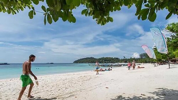 A beach with people, clear skies, and calm waters. - A Plus Hotel Koh Lipe - Hostel (Koh Lipe)