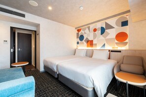 Ein Hotelzimmer mit Bett, einem Sessel, einem kleinen Tisch und einer Wanddekoration.
