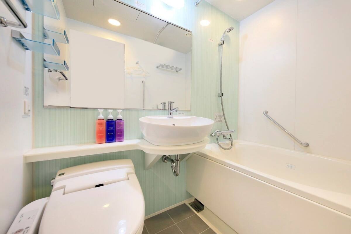 Une salle de bain avec un lavabo blanc, des toilettes, une baignoire et une douche.