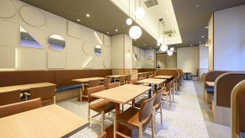 Um interior de restaurante moderno com mesas redondas e cabines, iluminação embutida e piso salpicado.