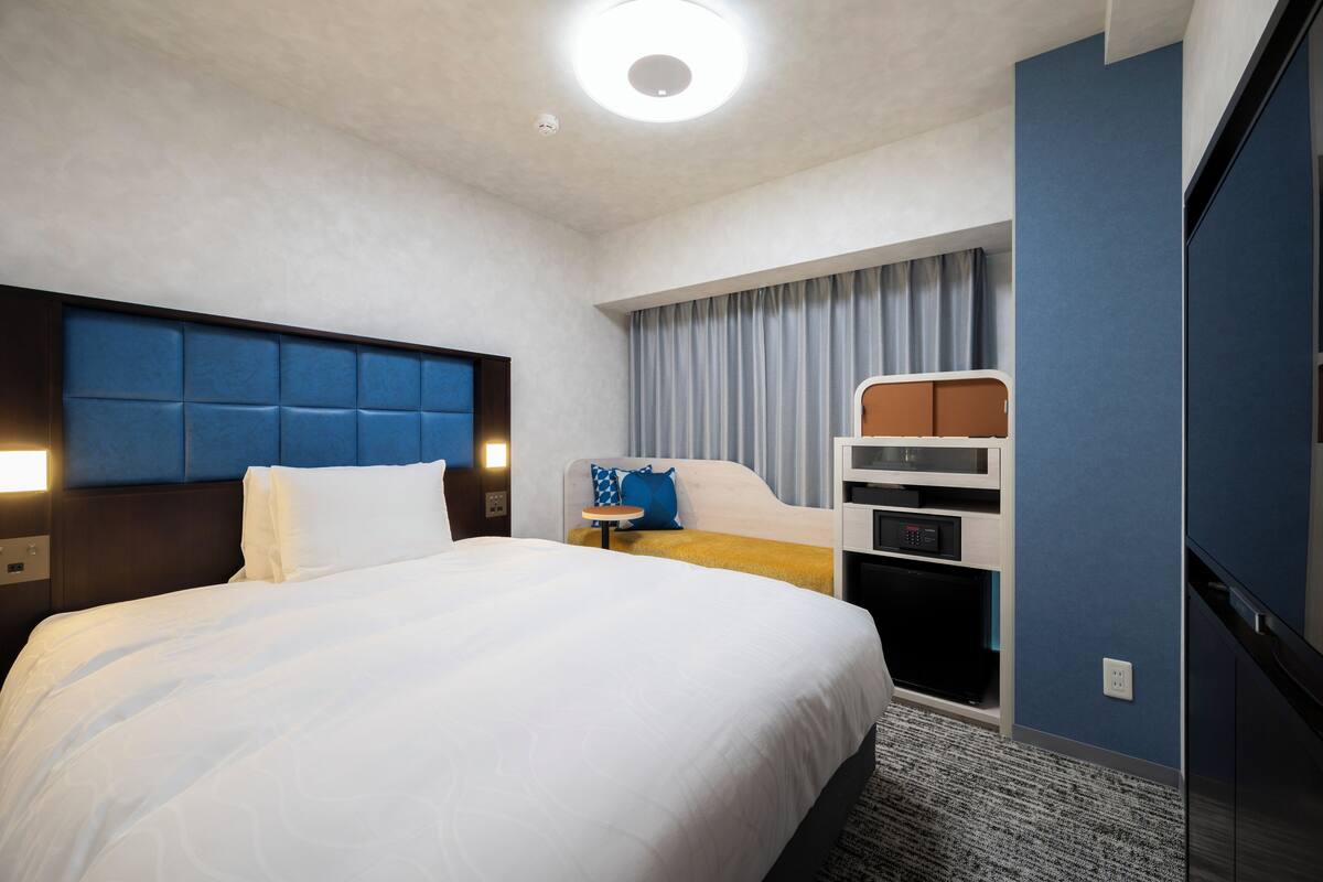 Une chambre d’hôtel avec un lit, un bureau, une télévision et une armoire.