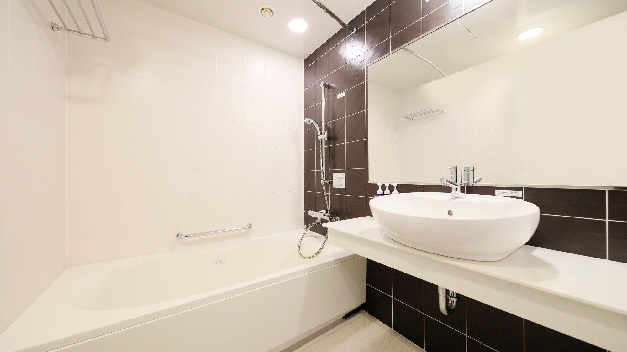 Un baño moderno con una bañera blanca, un espejo grande y un lavabo blanco.