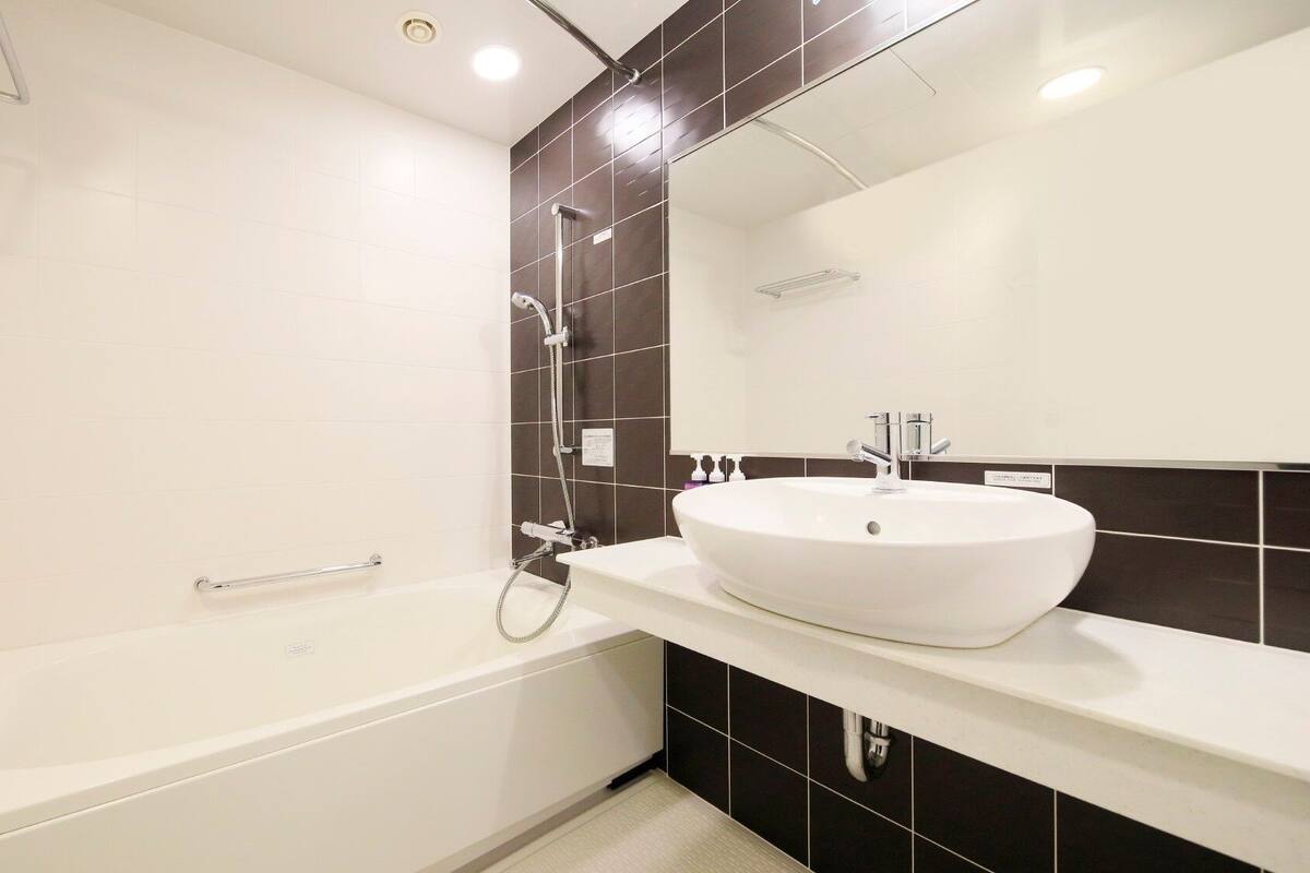 Une salle de bain moderne avec une baignoire blanche, un grand miroir et un lavabo blanc.