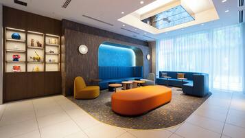 A modern lobby with a blue seating area, a reception desk, and a decorative wall with shelves.