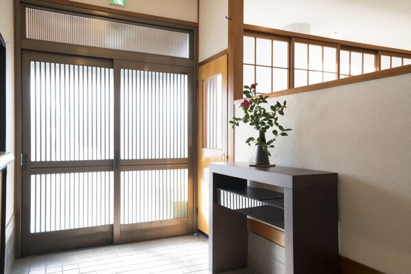 A traditional Japanese room with sliding doors, a tatami mat floor, and a small table with a potted plant.