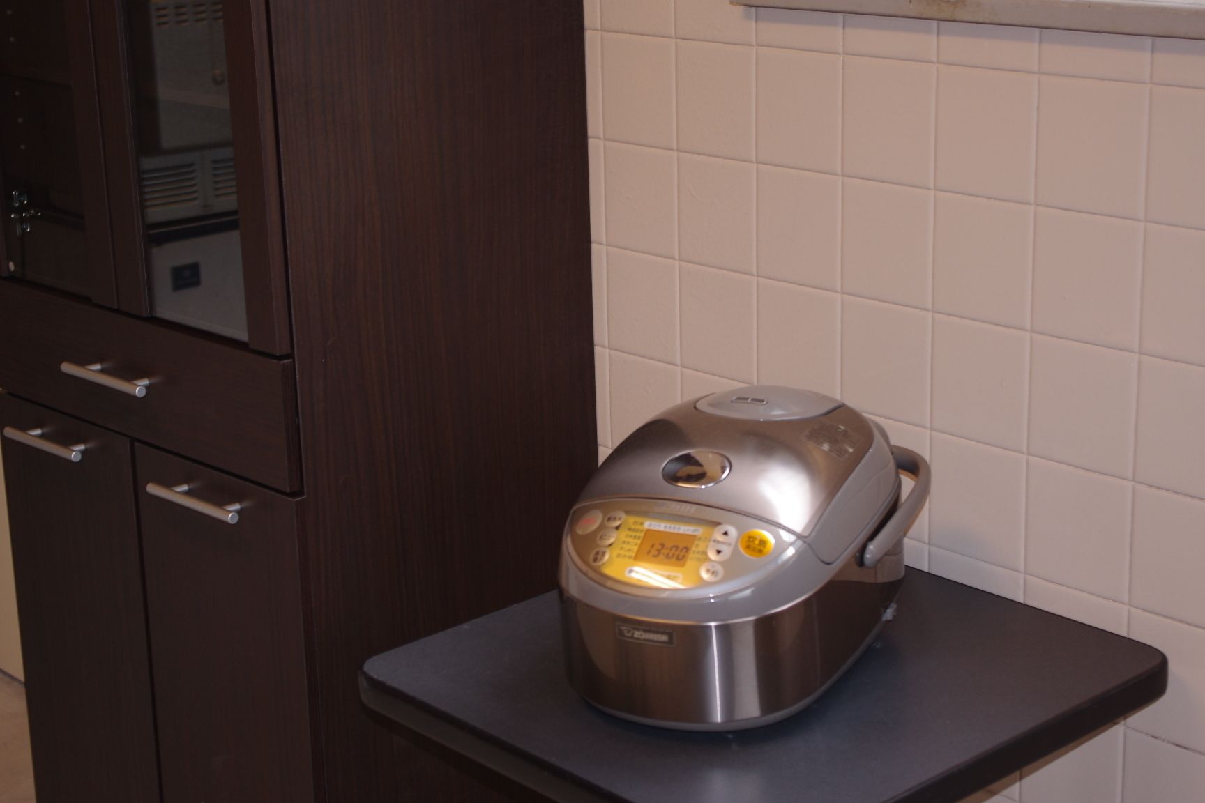 A kitchen with a stainless steel rice cooker on a countertop.