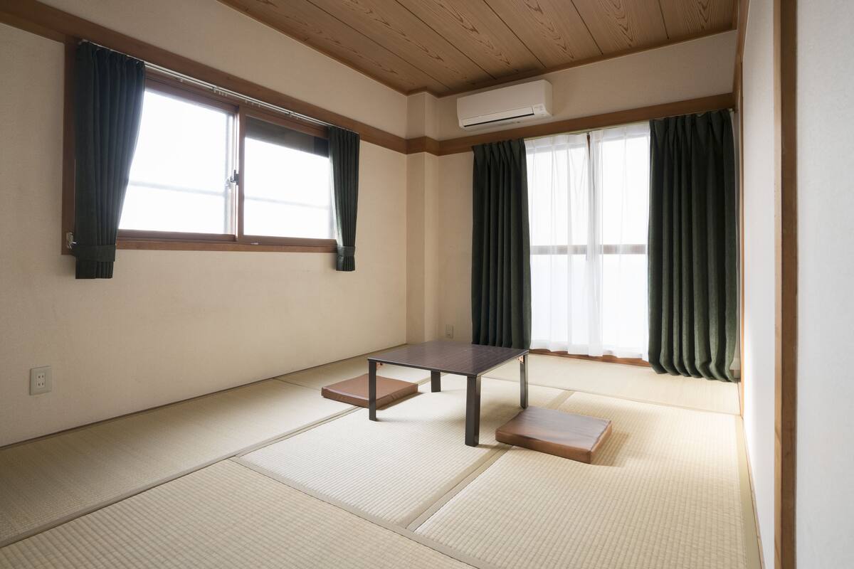 Una habitación con suelo de tatami, una mesa baja y un futón.