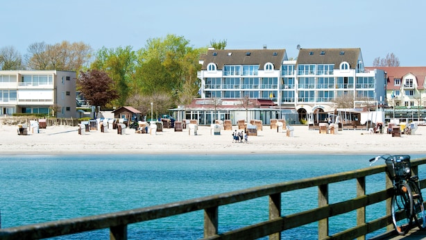 Un hotel frente al mar con vistas a la playa, varios pisos y diferentes zonas de estar.