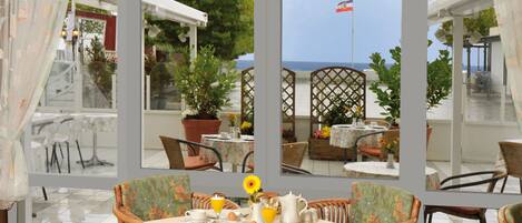 A dining area with wicker chairs and a table set for breakfast.