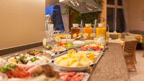 Un bufé con una variedad de alimentos y bebidas, como frutas, quesos y carnes.