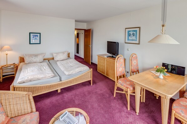 Une chambre d’hôtel comprenant un lit, un bureau avec un ordinateur, une télévision et une table à manger avec des chaises.
