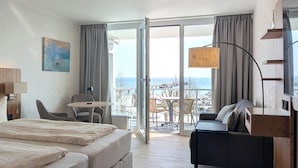 Una habitación de hotel con cama, sofá, mesa y vista al mar.