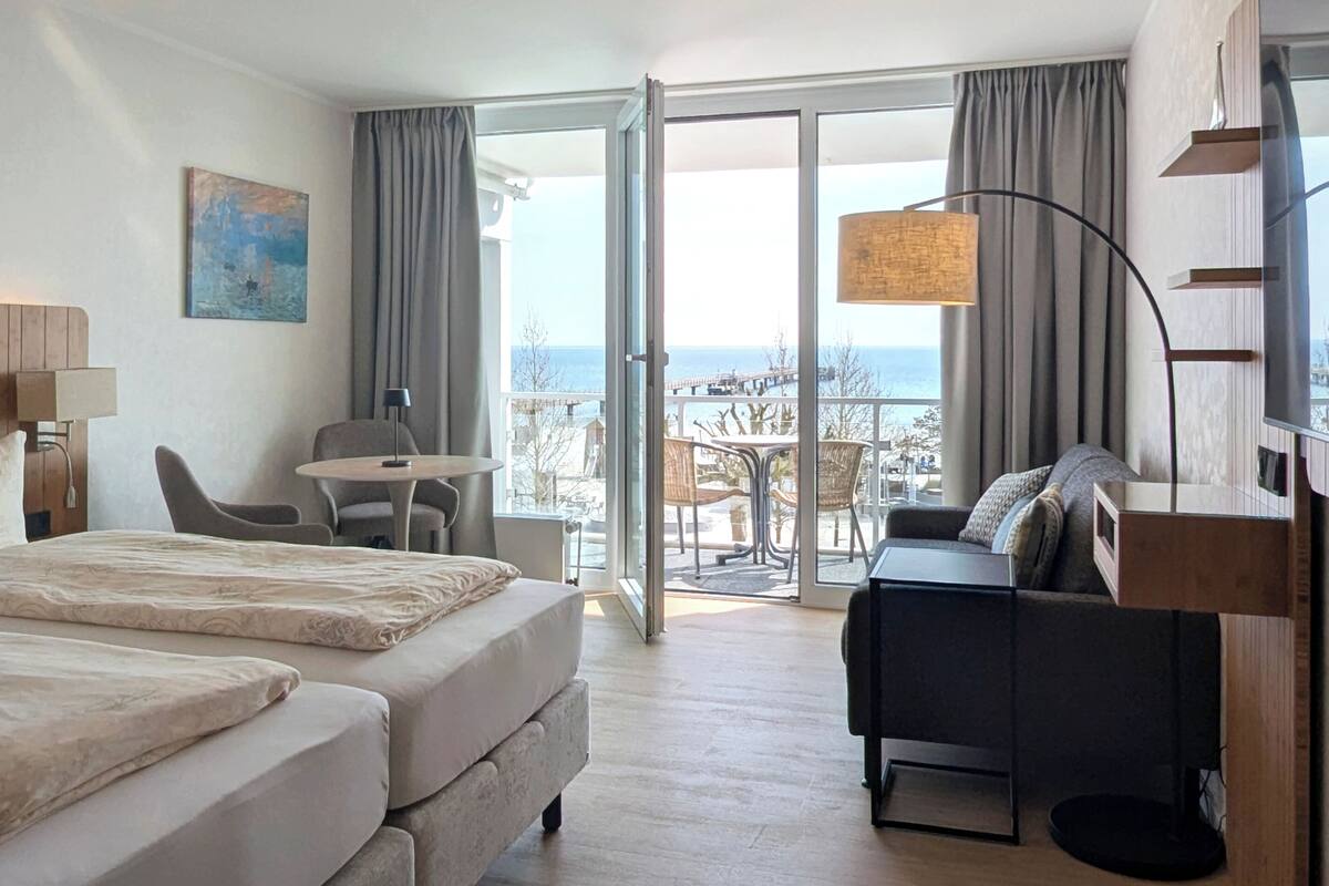 Ein Hotelzimmer mit Bett, Sofa, Tisch und Meerblick.