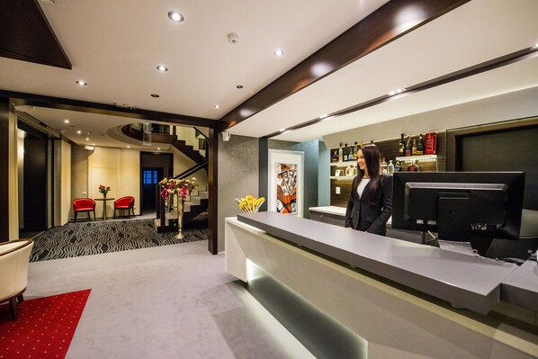 A hotel reception area with a modern design, featuring a reception desk, a staircase, and a bar area with various bottles. - Boutique Hotel Villa ZAUBER (Poprad)