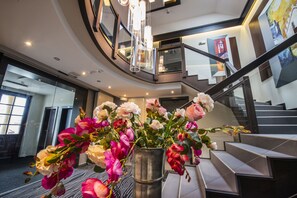 A modern interior with a staircase, a metal vase with flowers, and a large window. - Boutique Hotel Villa ZAUBER (Poprad)