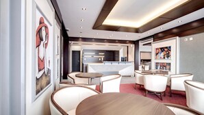 A modern hotel lobby with a reception desk, seating area, and artwork on the walls.