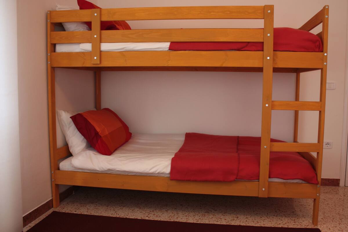 A bunk bed with two levels, each with pillows and a blanket.