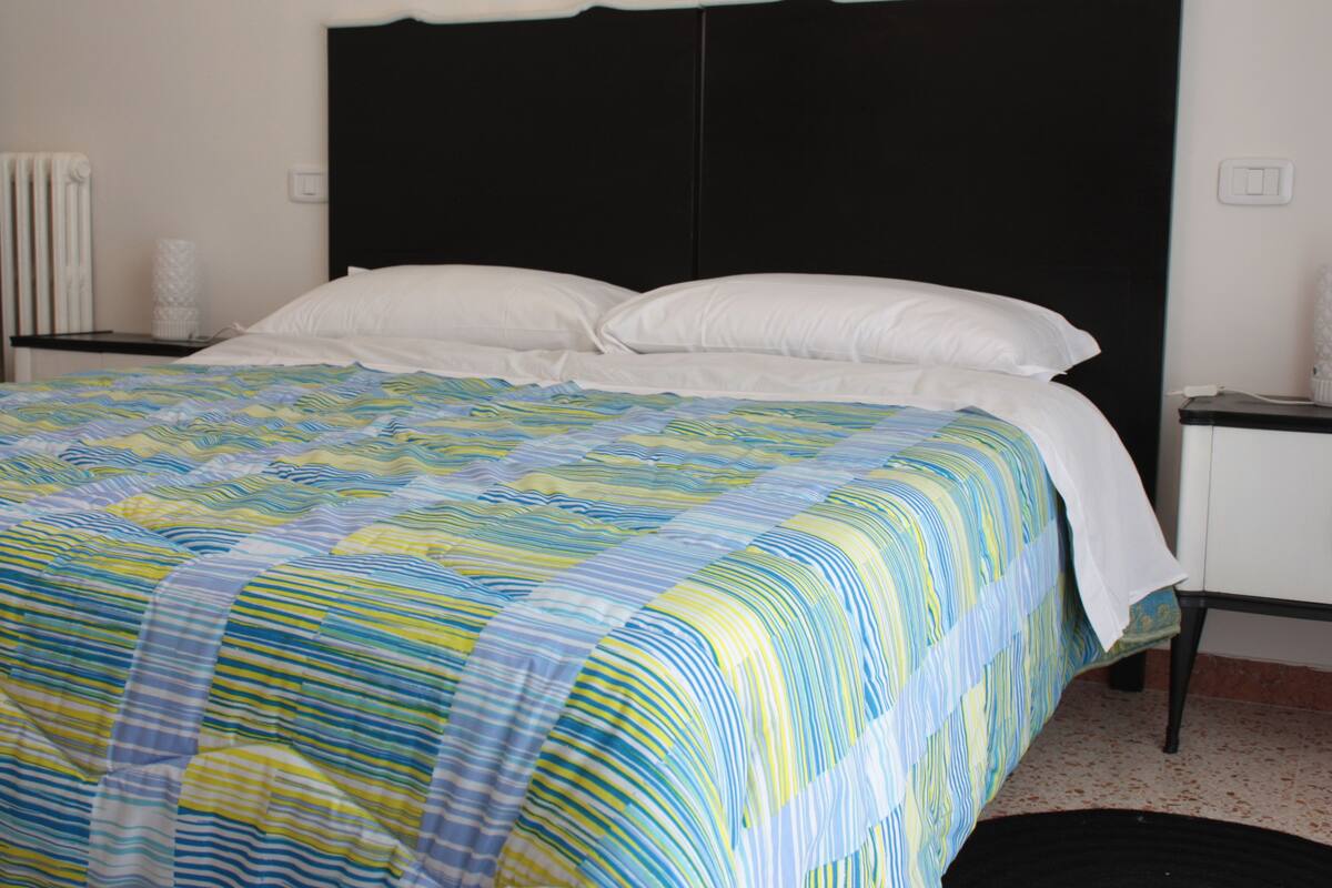 A bed with a striped bedspread, a black headboard, and white pillows.