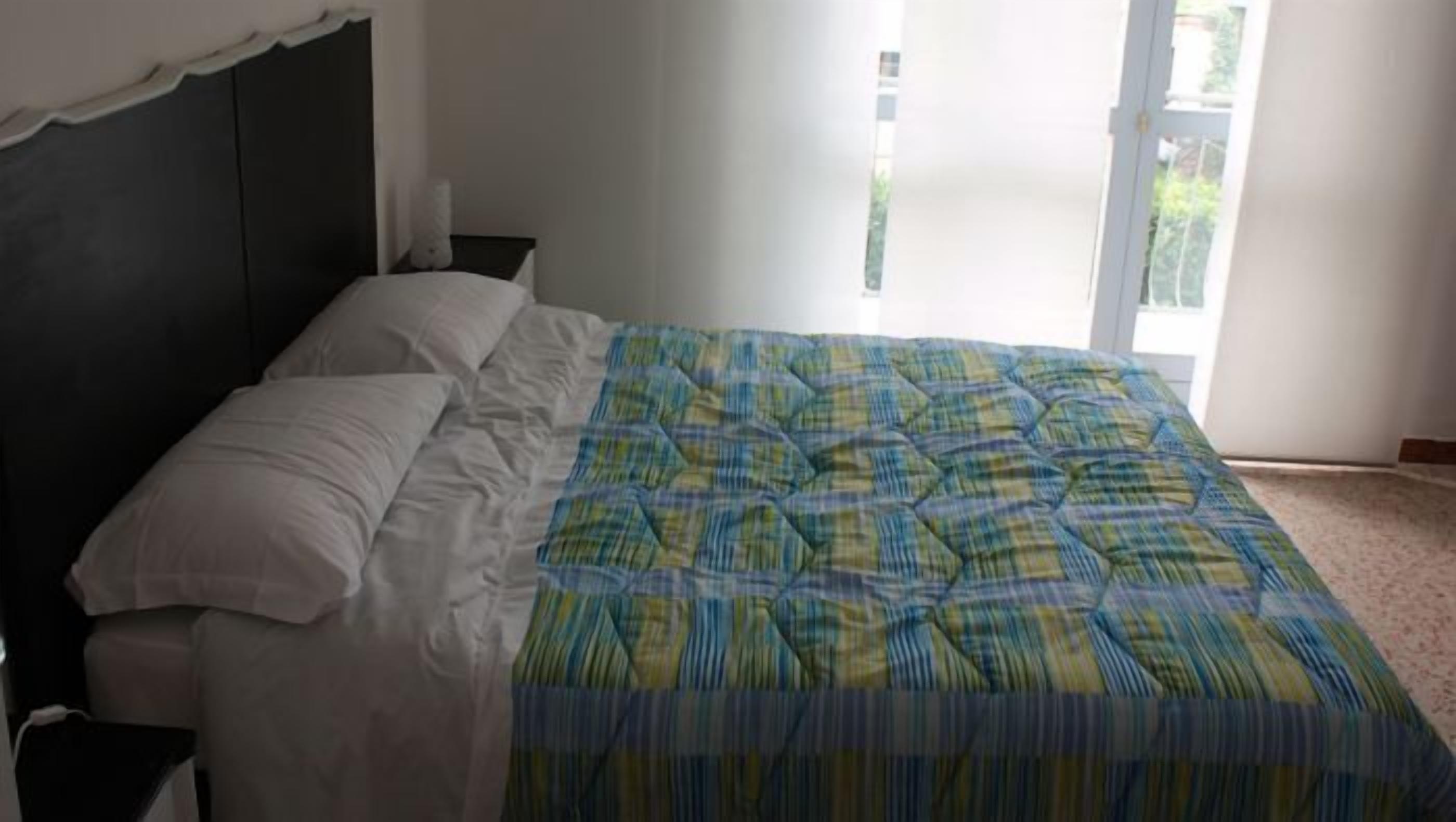 A bedroom with a bed, white pillows, and a plaid bedspread.