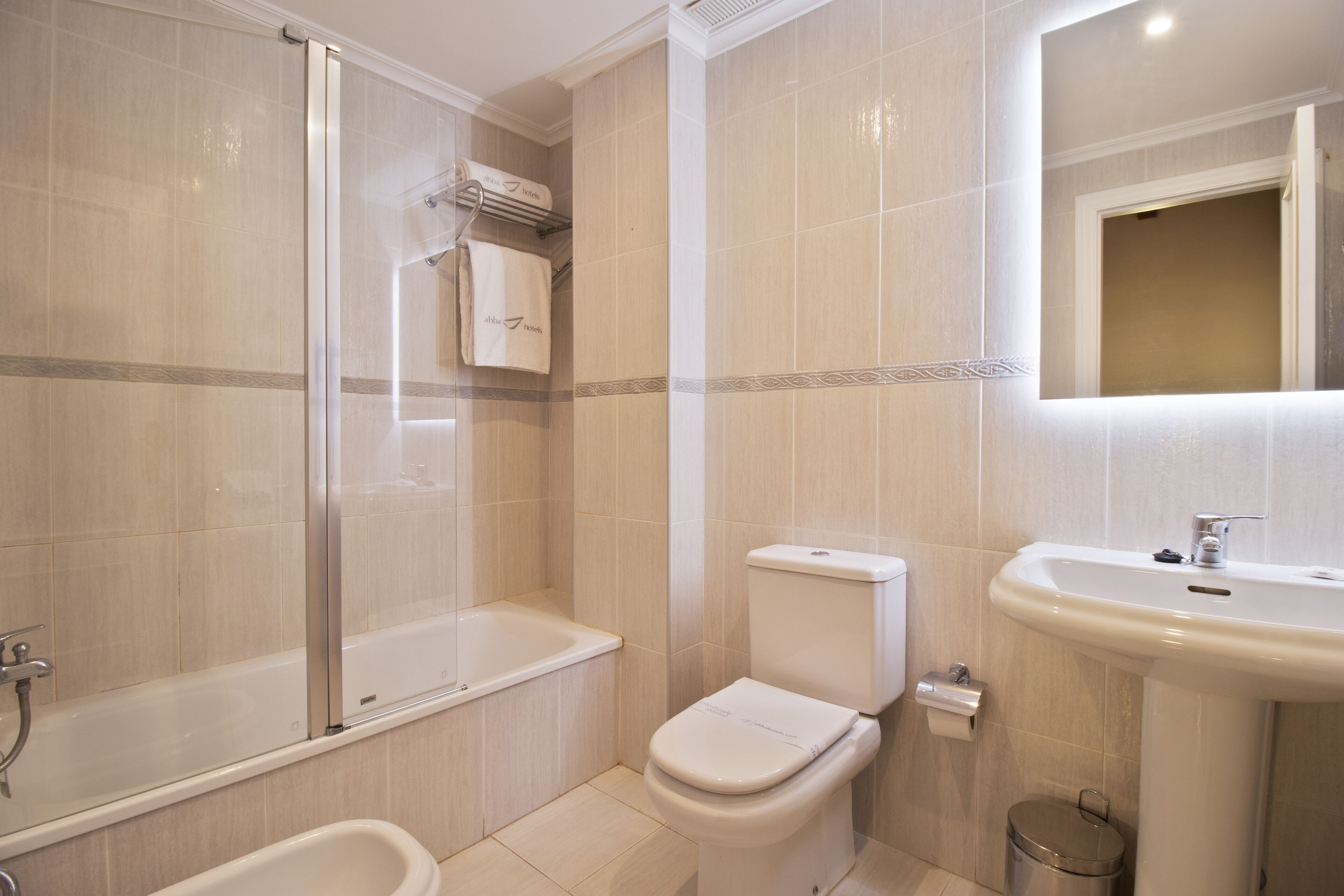 Een moderne badkamer met een bad, toilet en wastafel.