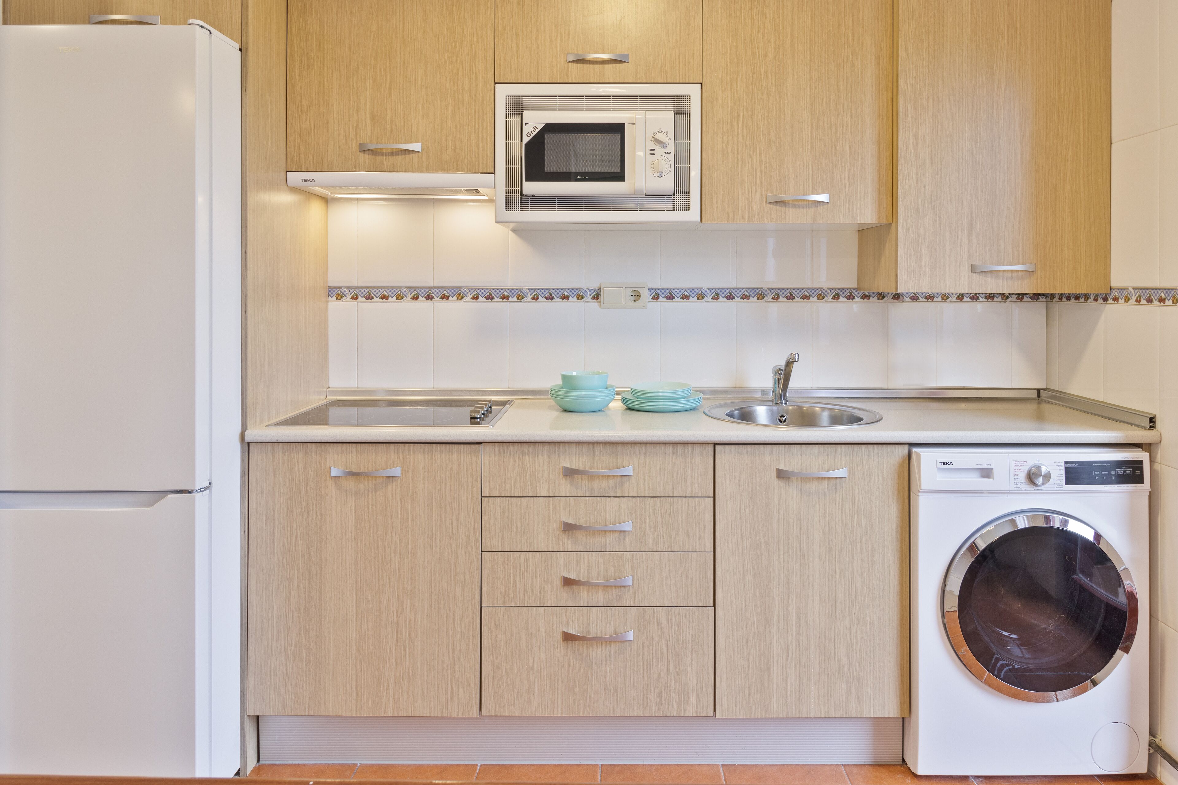 A modern kitchen with a built-in microwave, a sink, and a washing machine.