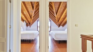A room with two beds, wooden ceiling beams, and a tiled floor. - Abba Comillas Apartments (Comillas)