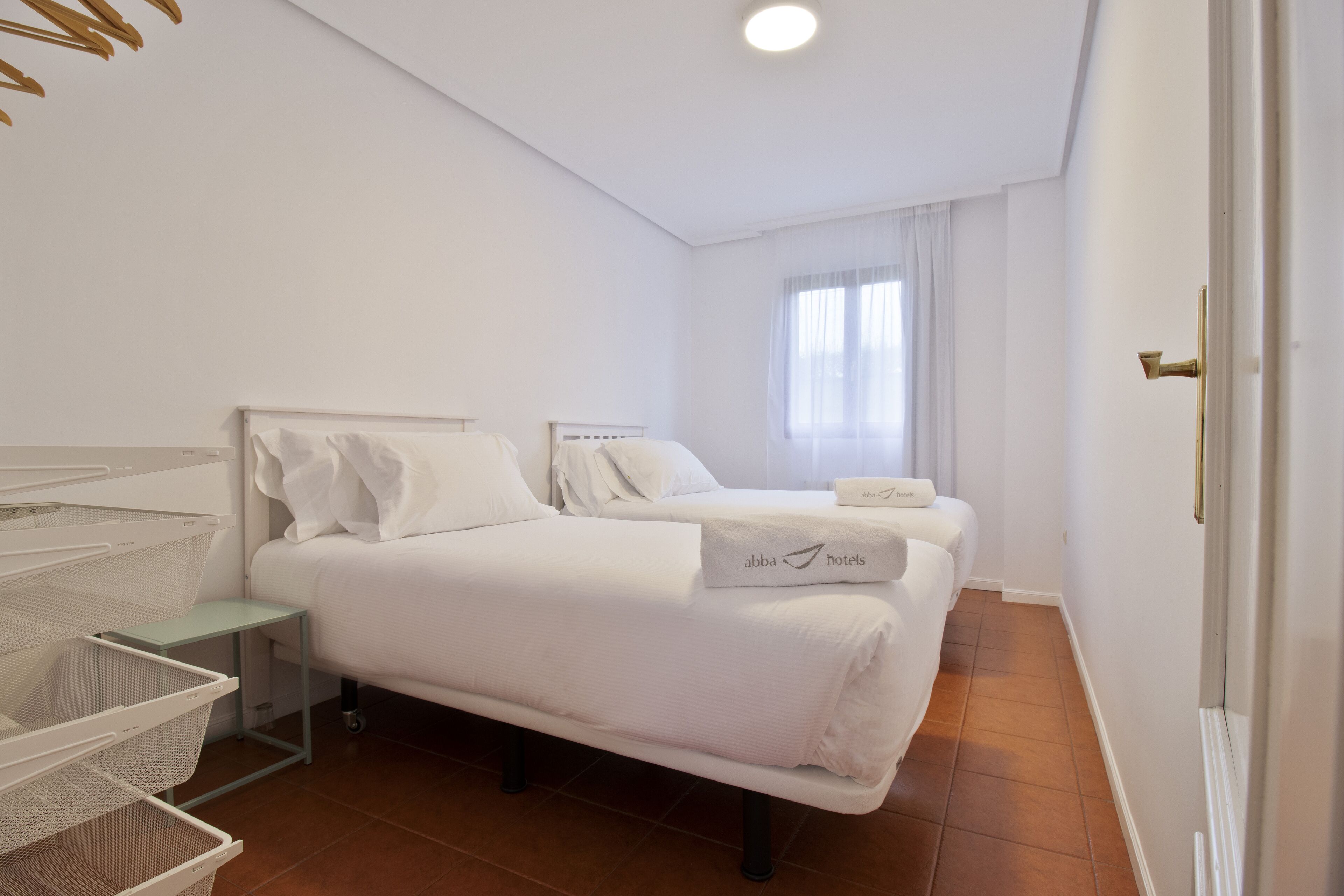Habitación de hotel con dos camas, una mesita y una cesta.