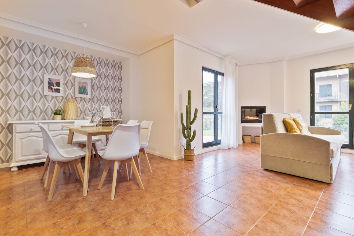 Un salón amplio con comedor, un gran ventanal y una planta de cactus.