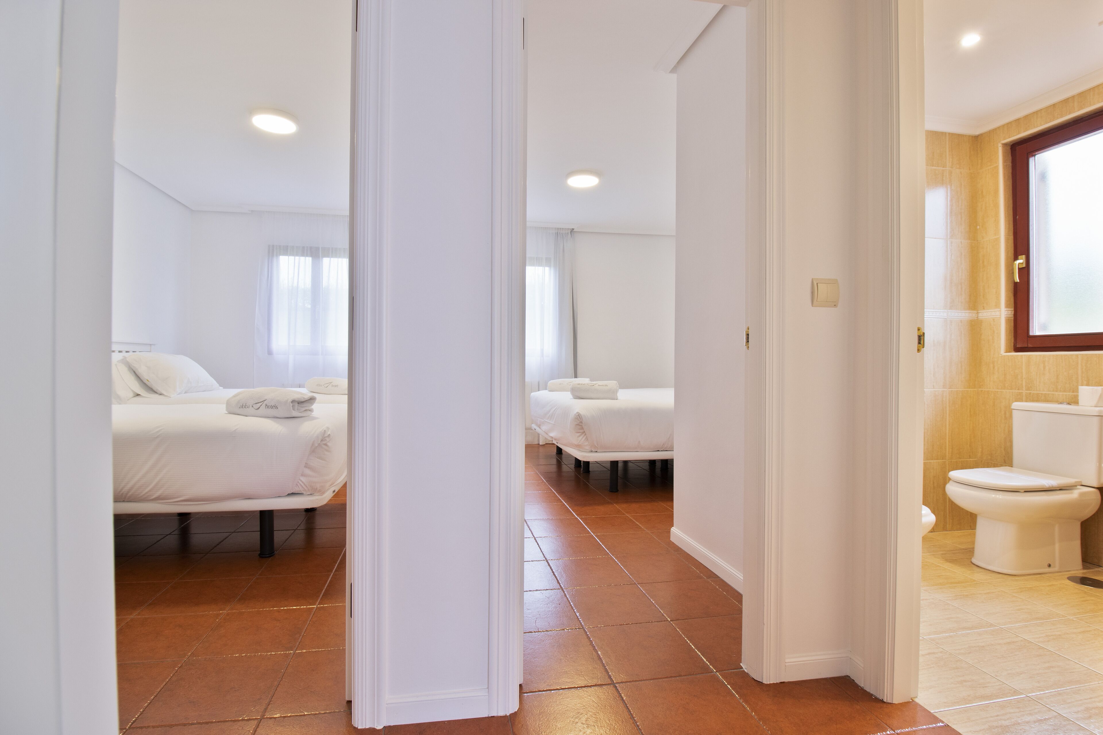 A hotel room with a bed, a bathroom with a toilet, and a shower.