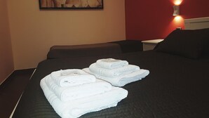 A hotel room with a bed, two folded towels, a painting on the wall, and a bedside lamp. - Airport Rooms Bari  (Bari)