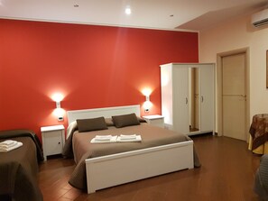 A bedroom with a large bed, two bedside tables, a wardrobe, and a small table with a tablecloth. - Airport Rooms Bari  (Bari)