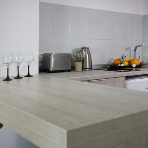 A kitchen with a toaster, kettle, and fruit bowl on the counter.